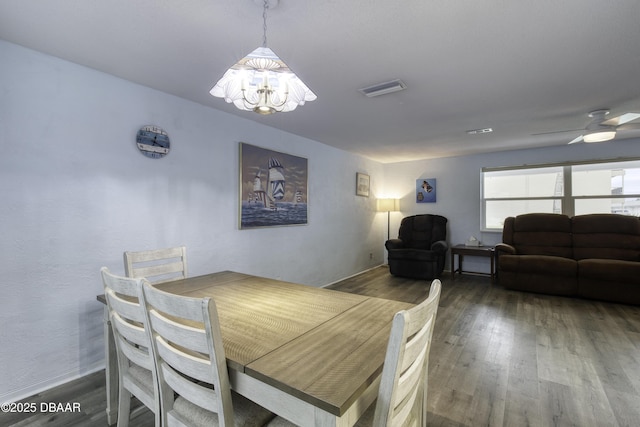 dining space with dark hardwood / wood-style flooring and ceiling fan with notable chandelier