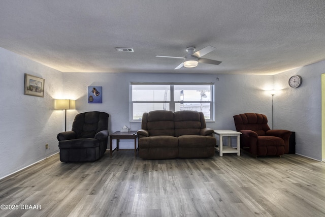 living room with ceiling fan, wood-type flooring, and a textured ceiling