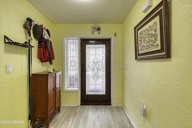 doorway to outside with a textured ceiling and light hardwood / wood-style floors