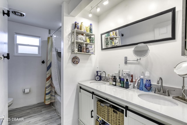 full bathroom with wood-type flooring, toilet, vanity, and shower / tub combo with curtain