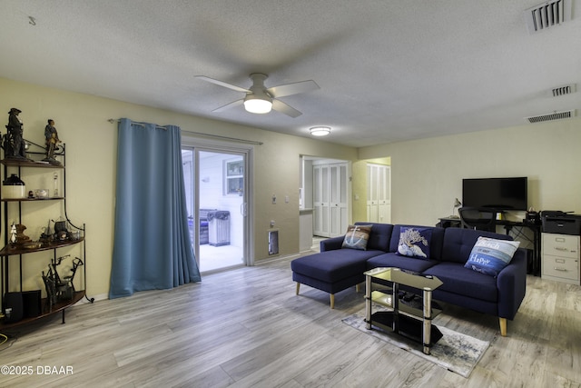 living room with ceiling fan, a textured ceiling, and light hardwood / wood-style floors