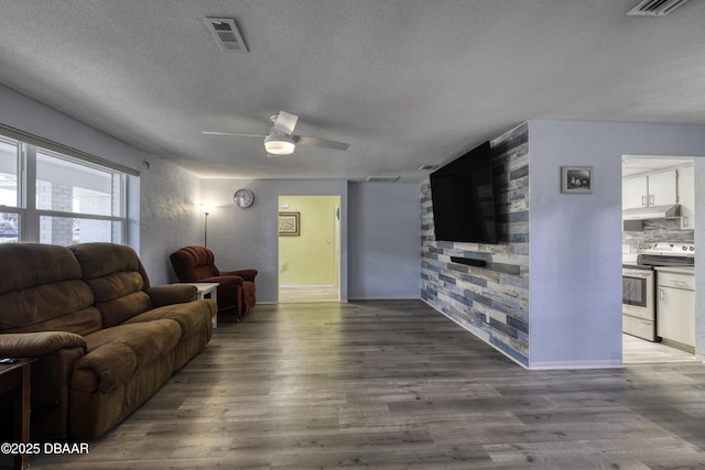 living room featuring a textured ceiling, ceiling fan, and hardwood / wood-style flooring