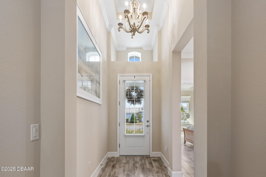 doorway to outside featuring hardwood / wood-style flooring, crown molding, and a notable chandelier