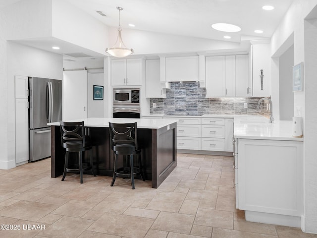 1601 S Riverside Dr, Edgewater, FL 32132 - kitchen featuring appliances with stainless steel finishes, a sink, backsplash, light countertops, and vaulted ceiling