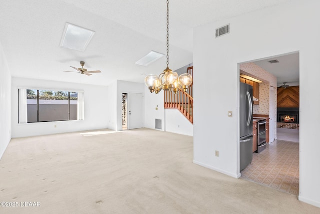 unfurnished living room featuring carpet, a large fireplace, a textured ceiling, and ceiling fan