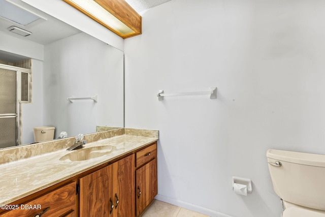 bathroom featuring vanity, walk in shower, tile patterned floors, and toilet