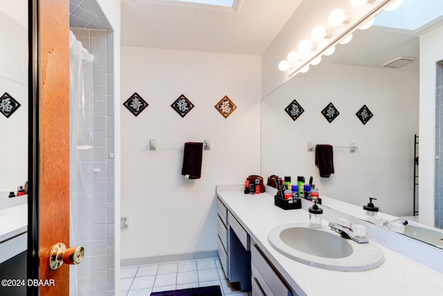 bathroom featuring vanity, a skylight, tile patterned floors, and a shower