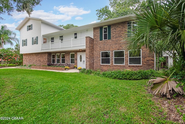 view of front facade with a balcony and a front yard