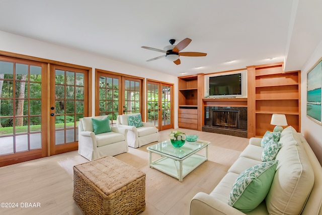 living room featuring a fireplace, french doors, ceiling fan, and light hardwood / wood-style flooring