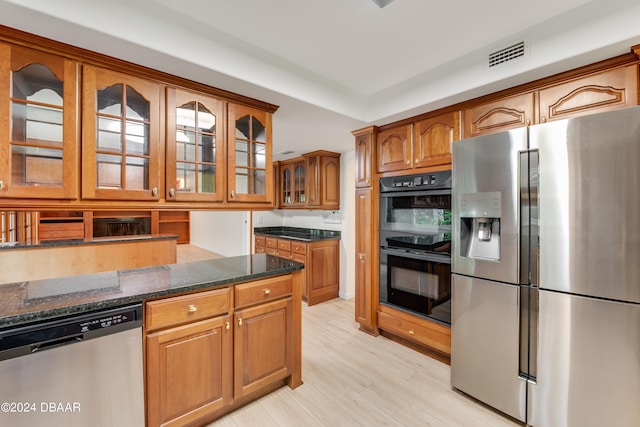 kitchen with dark stone counters, light wood-type flooring, and appliances with stainless steel finishes