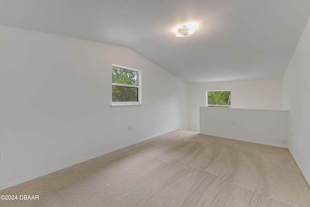 additional living space with vaulted ceiling and light colored carpet