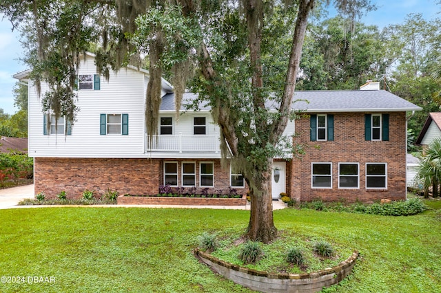 view of front of home with a balcony and a front yard