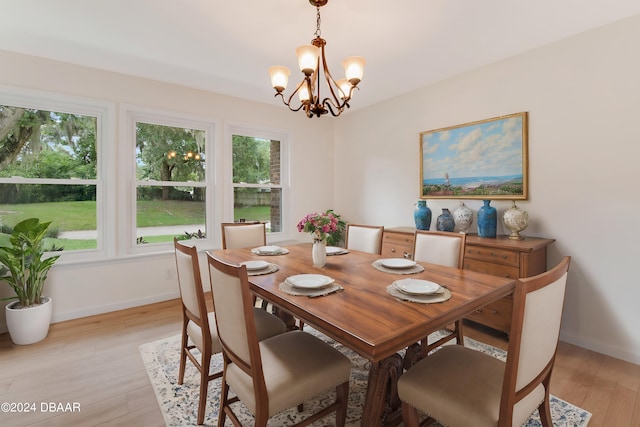 dining area with a wealth of natural light, an inviting chandelier, and light hardwood / wood-style flooring