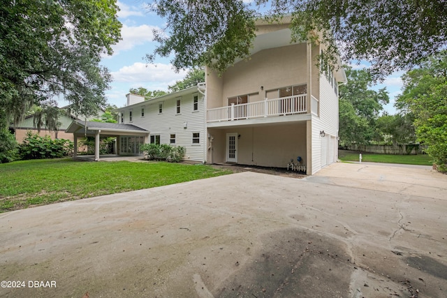 rear view of property featuring a garage, a yard, and a balcony