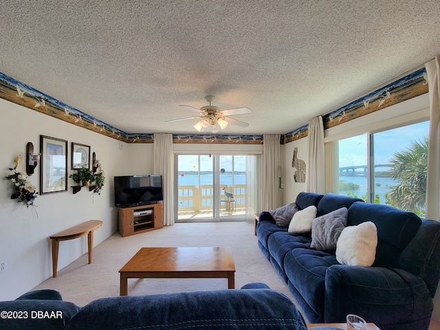 living room with a textured ceiling, light carpet, ceiling fan, and plenty of natural light