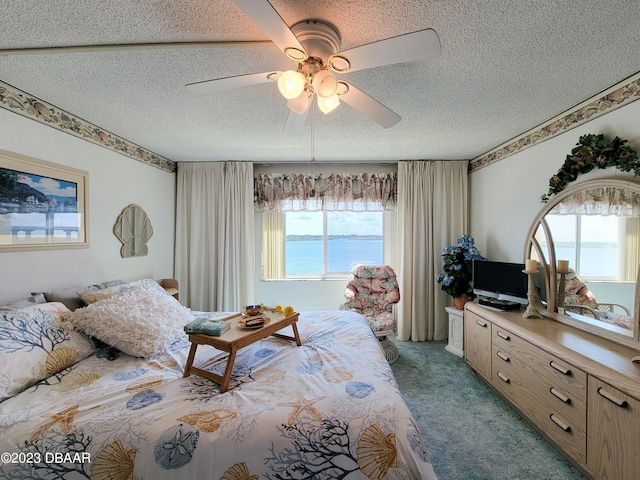 carpeted bedroom with a textured ceiling, multiple windows, and ceiling fan