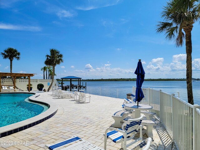 view of swimming pool with a patio area and a water view