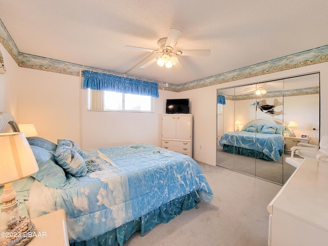 bedroom with a textured ceiling, light colored carpet, ceiling fan, and a closet