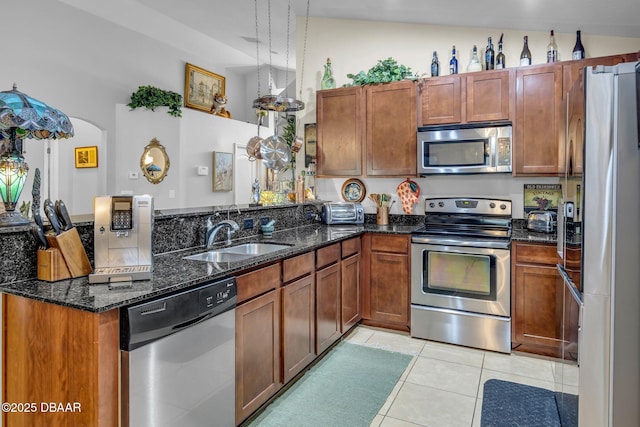 19343 Moorgate St, Orlando, FL 32833 - kitchen with stainless steel appliances, a peninsula, a sink, light tile patterned floors, and dark stone counters