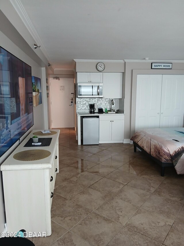 kitchen with tasteful backsplash, ornamental molding, stainless steel appliances, white cabinetry, and sink