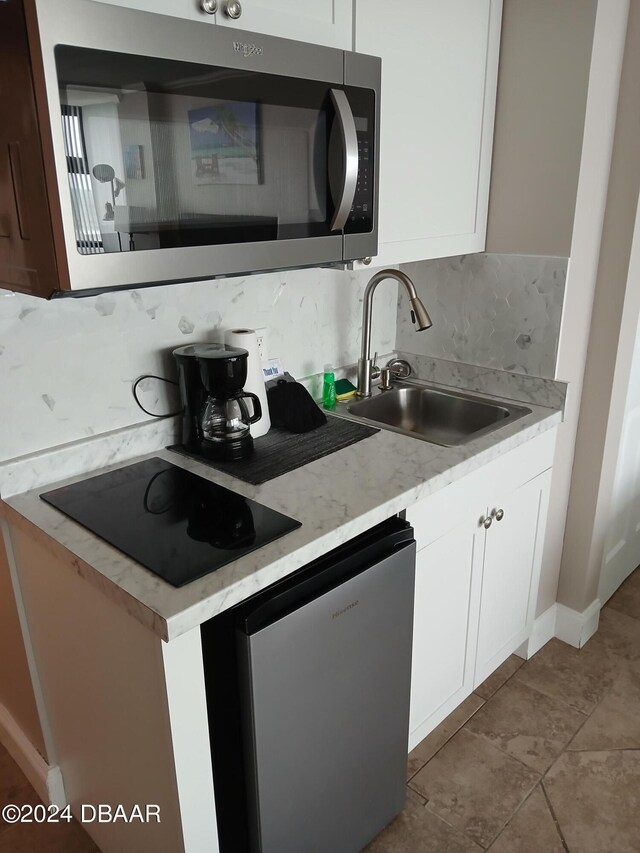 kitchen with stainless steel appliances, white cabinets, sink, and tasteful backsplash