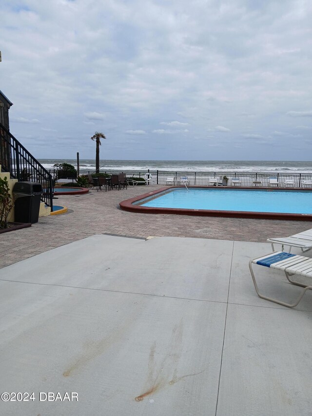 view of swimming pool with a water view and a patio area