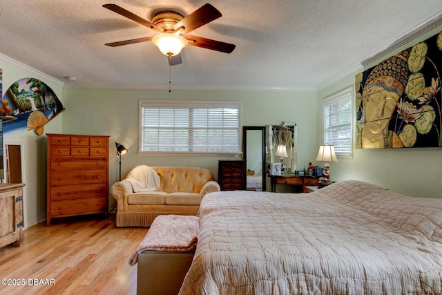 bedroom featuring light wood-style floors, ornamental molding, a textured ceiling, and a ceiling fan