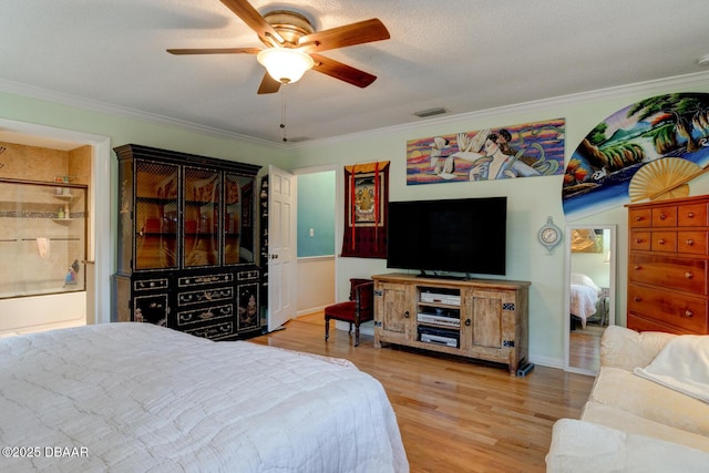 bedroom featuring wood finished floors, visible vents, a ceiling fan, ensuite bath, and crown molding