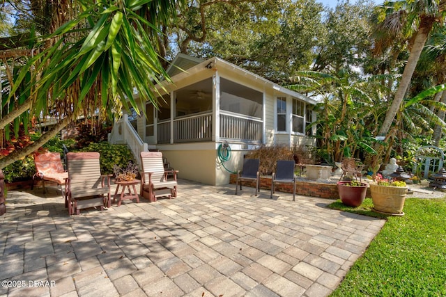 view of patio with ceiling fan and a sunroom