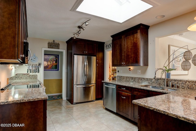 kitchen with light tile patterned floors, a skylight, a sink, appliances with stainless steel finishes, and light stone countertops