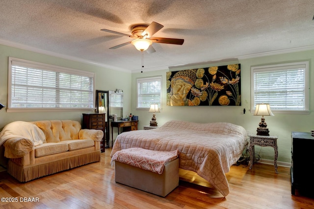 bedroom with a textured ceiling, ornamental molding, baseboards, and light wood-style floors