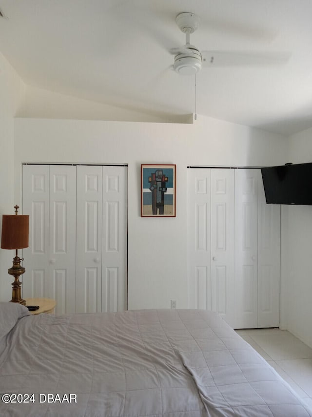 bedroom with vaulted ceiling, ceiling fan, and multiple closets