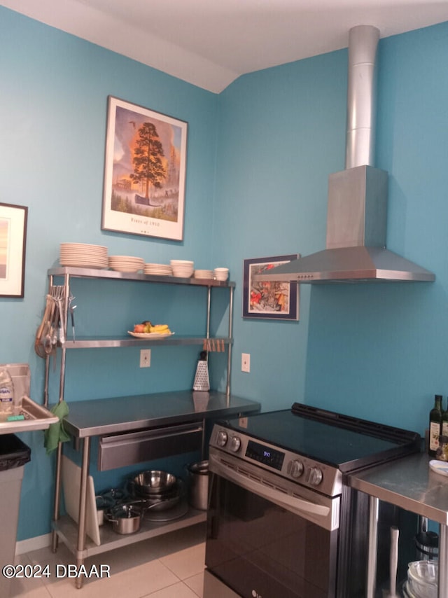 kitchen with light tile patterned flooring, stainless steel range with electric stovetop, and wall chimney range hood