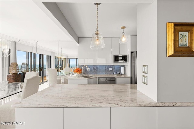 kitchen featuring white cabinetry, stainless steel appliances, light stone countertops, and sink