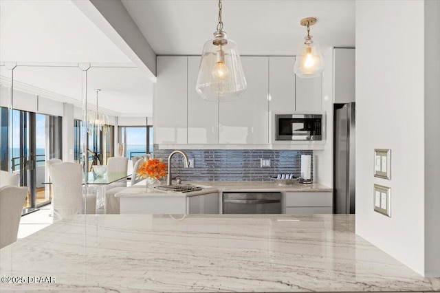 kitchen with sink, appliances with stainless steel finishes, white cabinetry, tasteful backsplash, and light stone countertops