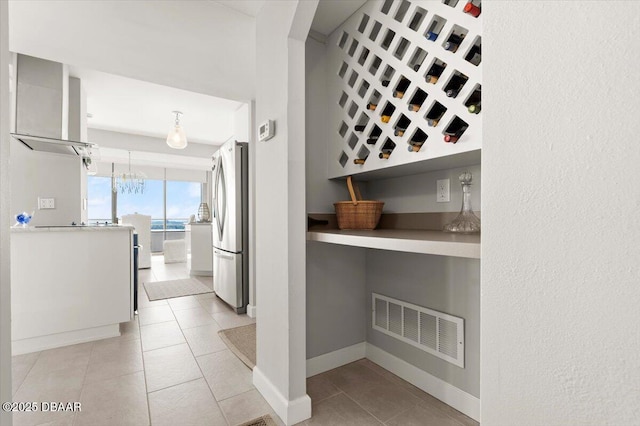 kitchen featuring stainless steel refrigerator, decorative light fixtures, an inviting chandelier, and light tile patterned floors