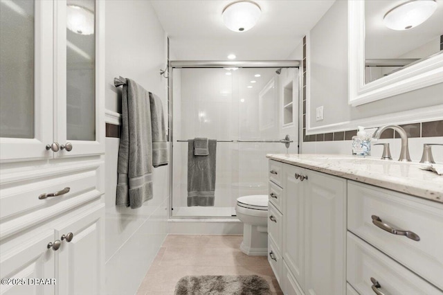 bathroom featuring tile walls, tile patterned flooring, vanity, an enclosed shower, and toilet