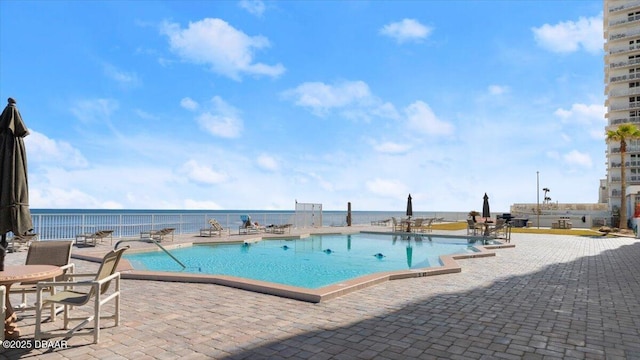 view of swimming pool featuring a patio and a water view