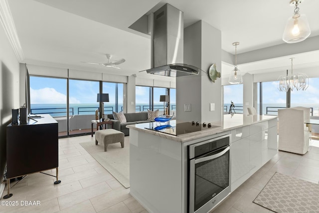 kitchen featuring a kitchen island, ventilation hood, white cabinets, oven, and hanging light fixtures