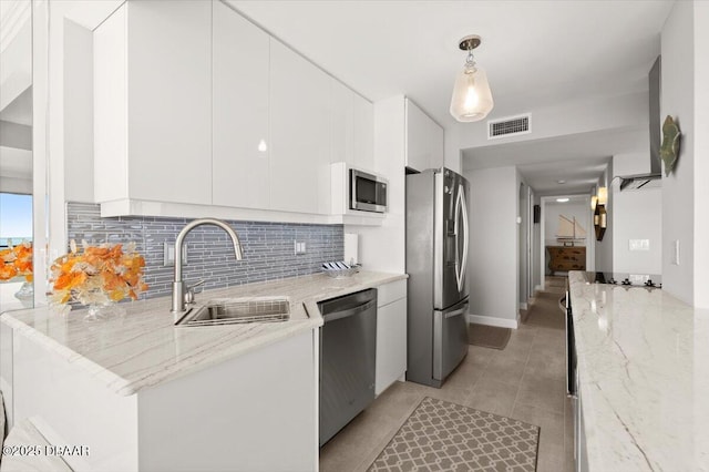 kitchen with hanging light fixtures, appliances with stainless steel finishes, white cabinets, and light stone counters