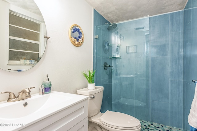 bathroom with vanity, toilet, a textured ceiling, and tiled shower