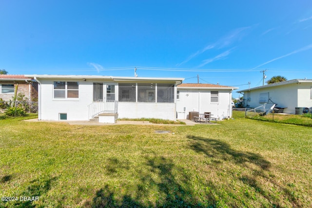 rear view of house with a lawn, a sunroom, and cooling unit