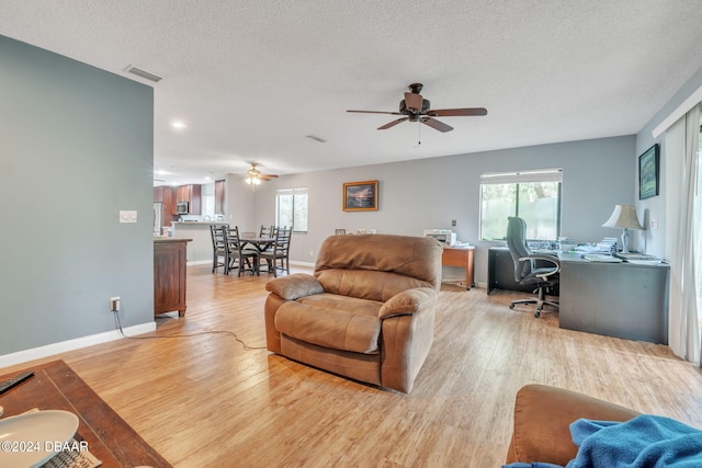 living room featuring light hardwood / wood-style floors, a textured ceiling, and ceiling fan