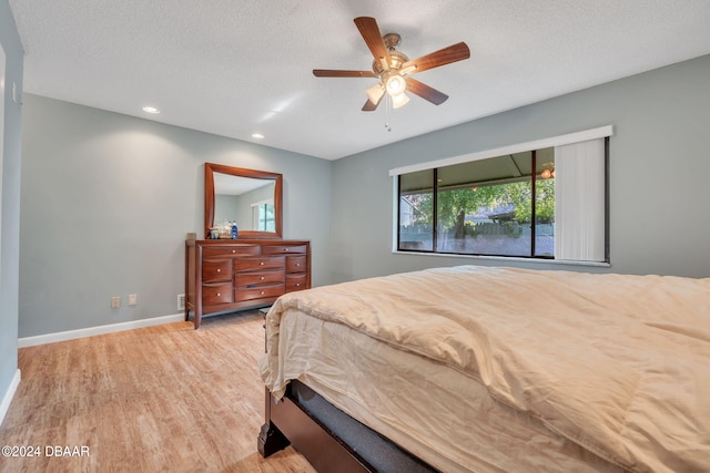 bedroom with a textured ceiling, light wood-type flooring, and ceiling fan