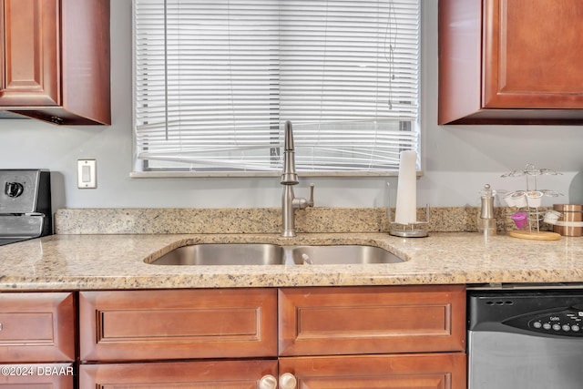 kitchen featuring stainless steel dishwasher, sink, and light stone counters