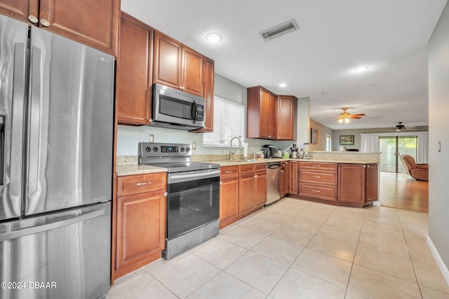 kitchen featuring light stone counters, light tile patterned flooring, stainless steel appliances, sink, and kitchen peninsula