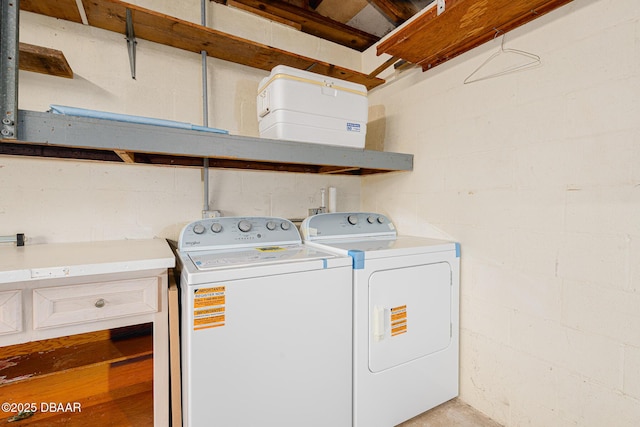 washroom featuring laundry area, washing machine and dryer, and concrete block wall