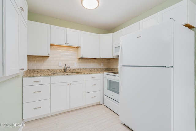 kitchen featuring tasteful backsplash, white appliances, a sink, and light stone counters