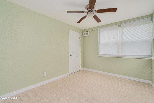 spare room featuring ceiling fan, visible vents, and baseboards