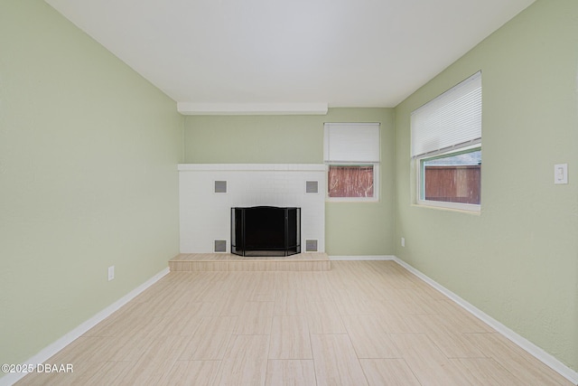 unfurnished living room with a fireplace with raised hearth, visible vents, and baseboards